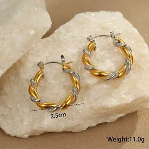 Macro shot of 2.5cm two-tone gold and silver twisted hoop earrings on white stones