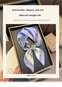 Close-up of elegant purple floral silk scarf tied in a bow inside a premium black gift box