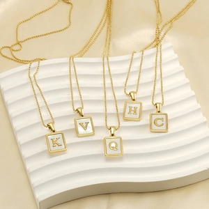 Golden stainless steel chain necklaces with square initial pendants on silk background