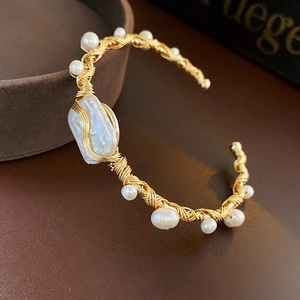 Detail of handcrafted gold wire wrapped bangle featuring a large baroque pearl