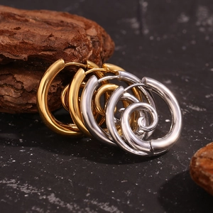 Detailansicht goldener und silberner Spiral-Ohrringe auf rustikalem Rindenhintergrund