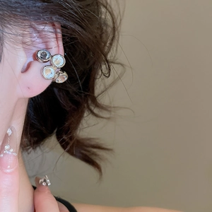 Close-up of a silver zircon ear cuff worn on the ear showing the four-stone hollow design