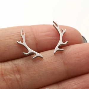 Macro shot of silver reindeer antler stud earrings held on fingertip for size scale