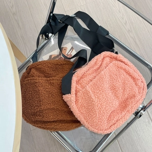 Detail view of brown and pink teddy fleece crossbody bags with adjustable nylon straps