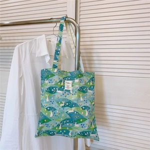 Detail of floral canvas tote bag featuring rabbit print and a stitched logo label