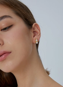 Close-up of a model wearing gold-plated snowman earrings with white pearls
