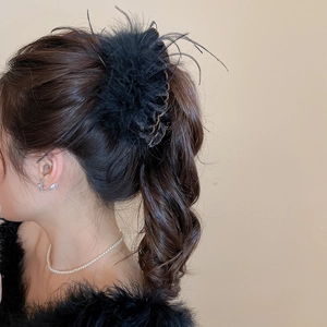 Detail shot of a black feather tassel hair clip styled on a woman's ponytail