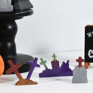 Primer plano de dijes de Halloween en forma de cruz y lápida con brillo sobre madera
