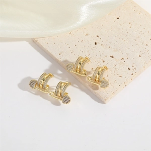 Luxe gold safety pin earrings with pavé crystals set against silk for a trendy aesthetic