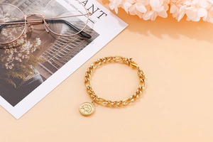 Close-up of golden Tree of Life coin pendant and thick Cuban chain on warm background