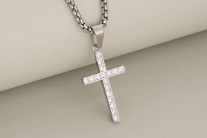 Detailed view of silver cross pendant with sparkling zircon insets on box chain necklace