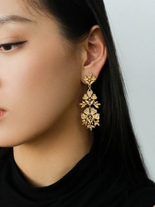 Macro detail of vintage hollow flower tassel earrings with three-layer metal floral pattern