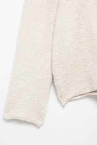 Gros plan détaillé du cardigan en tricot crème avec fausse fourrure épaisse et polaire douce