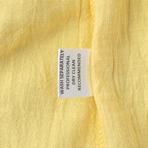 Detail of yellow textured fabric showing washing label with care instructions for the set
