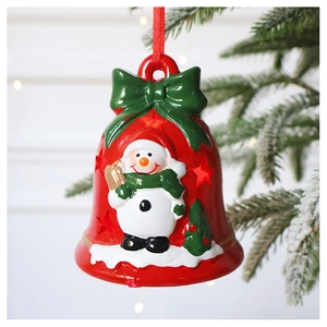 Close-up of a festive red Christmas bell with snowman relief hanging on a tree branch
