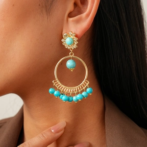 Detail of bohemian gold hoop earrings with turquoise beads and crystal flower studs