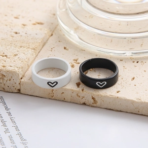 Close-up of minimalist black and white couple rings with heart patterns on stone base