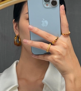 Détail de bagues en titane doré avec cristaux colorés et boucles d'oreilles ambrées