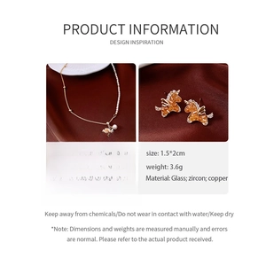 Detail view of Pegasus pendant necklace and earrings with orange glass and white zircon stones