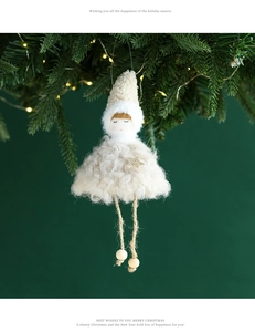 Close-up of a plush angel doll ornament hanging on a Christmas tree with warm lights