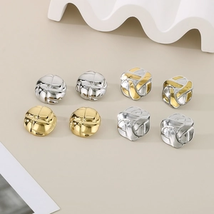 Detailed macro view of geometric round and square metal earrings in gold and silver finish