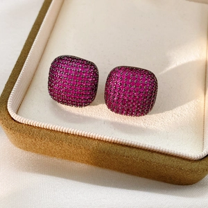 Gros plan de boucles d'oreilles carrées en zircon rose et métal noir dans un écrin