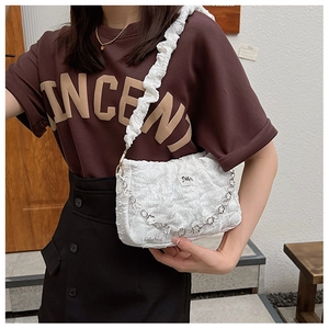 Detail of white bubble texture shoulder bag with silver floral chain and pleated strap