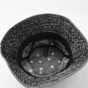 Detailed view of daisy flower embroidery on washed denim fabric of a gray bucket hat