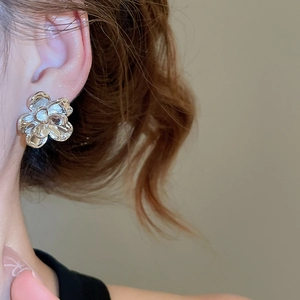 Close-up of polished silver flower earring worn on model featuring a 3D floral design