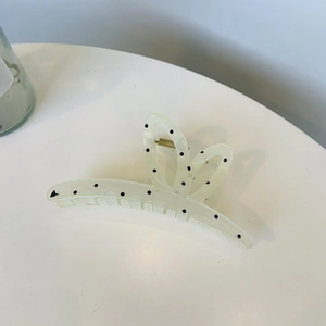 Close-up of a cream translucent hair claw clip with black polka dots and metal spring detail
