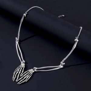 Macro detail of silver skeleton hand pendant with gothic metal bone texture