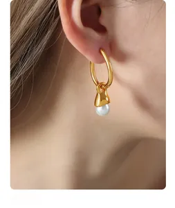 Detail of a minimalist gold-plated hoop earring featuring a lustrous white round pearl