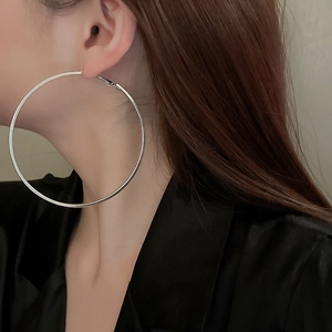 Macro side view of oversized silver metallic hoop earrings with polished geometric finish