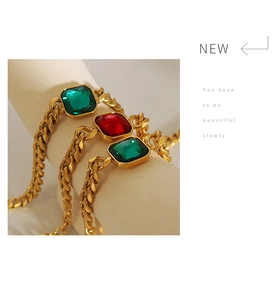 Close-up of gold plated Cuban link bracelets with green and red square crystal stones
