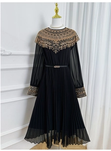 Detailed view of luxury gold beadwork and embroidery on a black pleated chiffon dress