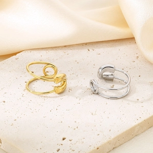 Macro view of gold and silver safety pin rings on a textured stone surface background