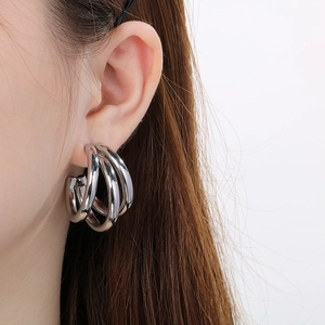 Close-up of triple-hoop silver earrings on model, featuring a polished hollow tube design