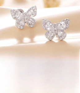 Detailed macro view of silver titanium steel butterfly stud earring with clear zircon inlay