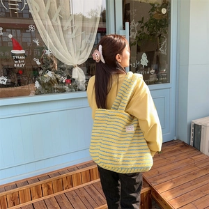 Outdoor shot of plush yellow and blue striped tote bag with squeak tag detail