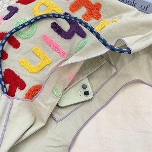Macro detail of tote bag interior pocket with purple trim holding a smartphone