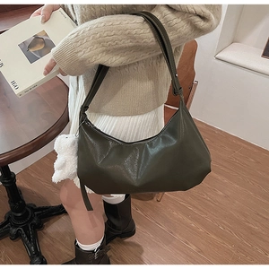Detail of dark green PU leather crescent hobo bag with plush bear charm and silver zipper