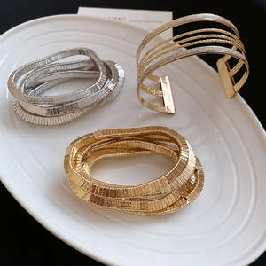 Macro detail of gold and silver layered coil bracelets and textured wide cuffs