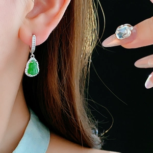 Close-up of green jade Buddha drop earring with silver clasp and inlaid zircons