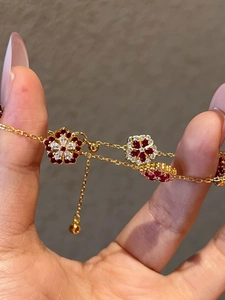 Macro shot of gold plated flower bracelet featuring red zircons and adjustable slider