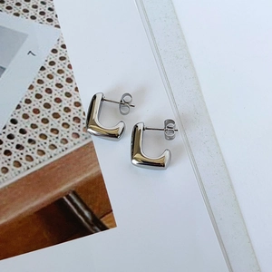Close-up of minimalist silver-toned U-shaped stainless steel earrings on a book