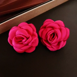 Detail of rose stud earrings with satin texture and elegant gold metallic edging