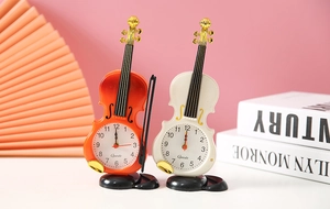Dettaglio delle sveglie a forma di violino arancione e bianco su una scrivania rosa