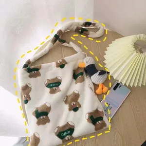 Detail of soft white plush tote bag with cartoon bear print and a cute duck doll charm
