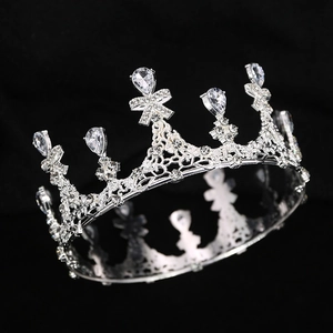 Close-up of silver crown with rhinestones and pear-shaped crystals on black background