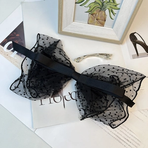 Close-up of black polka dot mesh bow hair clip with elegant French style ribbon design